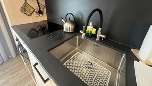 A modern kitchen with a stainless steel sink, a kettle, and a black faucet. - 2 - Bormio Al Pradais Apartments - WEST Garden (Bormio)