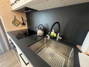 A modern kitchen with a stainless steel sink, a kettle, and a black faucet. - 2 - Bormio Al Pradais Apartments - WEST Garden (Bormio)