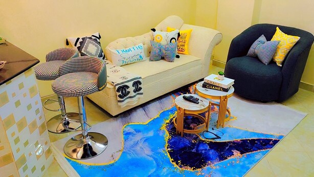 Un salon comprenant un canapé, des fauteuils, une table basse, un tapis à motifs et une petite table d’appoint avec un livre.