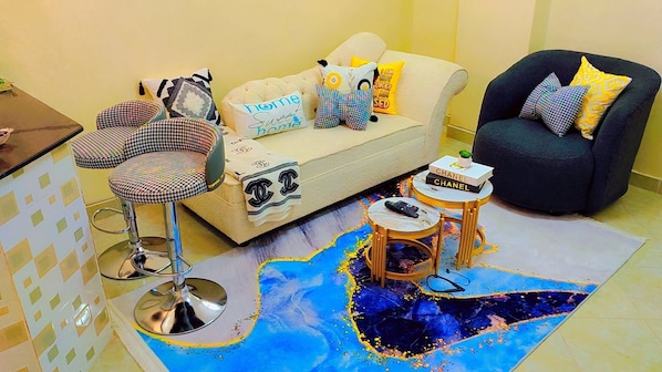 A living room with a sofa, armchairs, a coffee table, and a patterned rug. - Charming 1-bedroom apartment in vibrant Eastern bypass perfect for your stay (Nairobi)