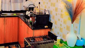 Une cuisine avec des meubles de rangement en bois, une cuisinière à gaz, un plan de travail noir et un vase décoratif.