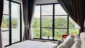 Une chambre avec un grand lit, un balcon avec vue et une fenêtre avec des rideaux.