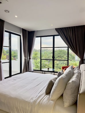 Ein Schlafzimmer mit einem großen Bett, einem Balkon mit Blick und einem Fenster mit Vorhängen.