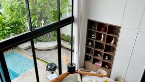 Un salon moderne avec vue sur la piscine, un coin repas et une bibliothèque intégrée.