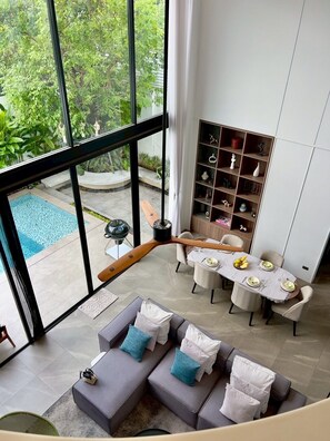 Ein modernes Wohnzimmer mit Blick auf einen Pool, einem Essbereich und einer eingebauten Bücherwand.