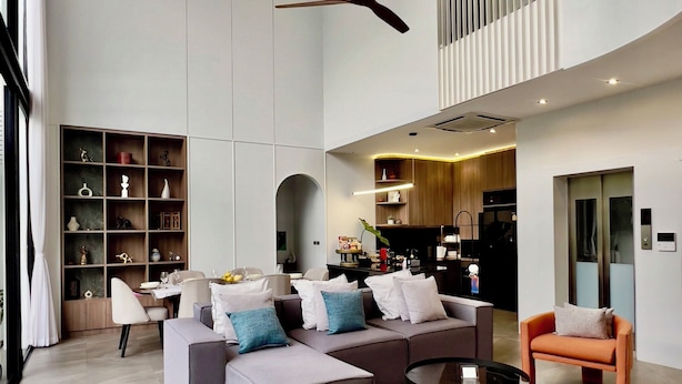 Un vaste espace de vie doté d’un haut plafond, d’un ventilateur de plafond, d’une cuisine intégrée et d’un coin salon avec une table basse.