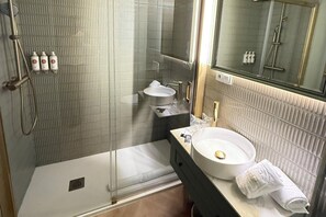 A bathroom with a glass-enclosed shower, a sink with a gold faucet, and a mirror above the sink. - Holiday home - Detached (Alicante)