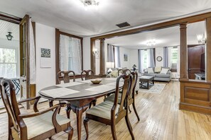 Ein Essbereich mit einem runden Tisch, Holzstühlen und einer Couch im Hintergrund.