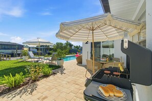 A backyard with a grill, lounge chairs, a pool, and umbrellas. - Waterfront Gem w/ Boat Dock, Pool in Apollo Beach (Apollo Beach)