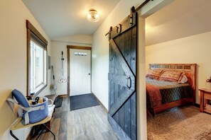 Ein Schlafzimmer mit einem Bett, einer Holztür, einem Sessel, einem Fenster und einer Tür.
