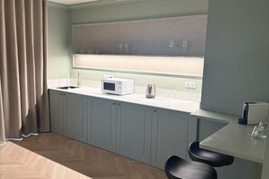 Een moderne keuken met een magnetron, waterkoker en barkrukken.