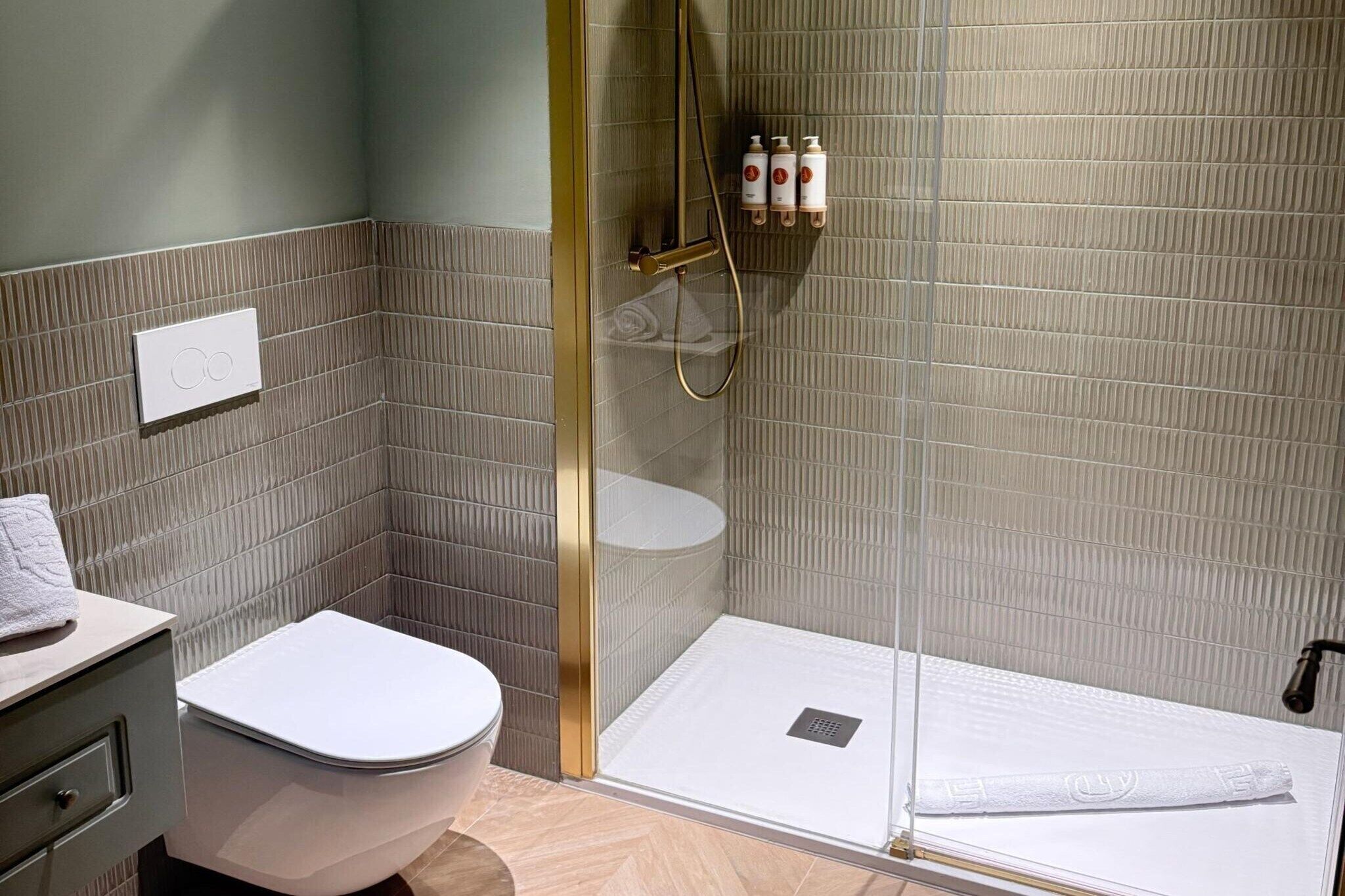 Une salle de bain équipée de toilettes, d’un espace de douche et d’un porte-serviettes avec des bouteilles.