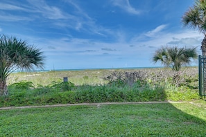 A grassy area with palm trees and a view of the ocean. - Walkable Cocoa Beach Condo w/ Ocean Views (Cocoa Beach)