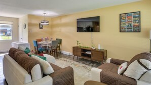 A living room with a sofa set, a dining table with chairs, a TV mounted on the wall, and a small cabinet. - Easy Access to Parks, Hospital: St Louis Home (St. Louis)