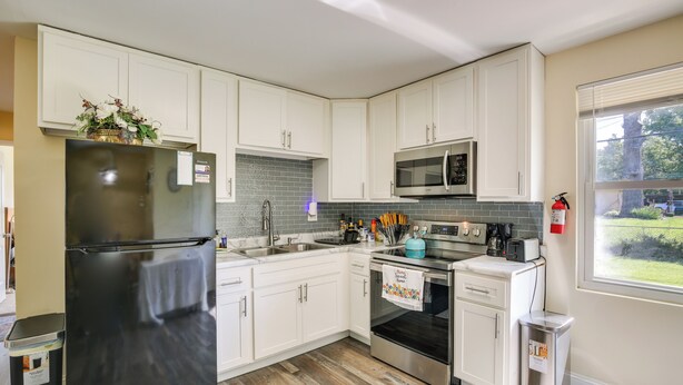 A modern kitchen with white cabinets, stainless steel appliances, and a tiled backsplash. - Easy Access to Parks, Hospital: St Louis Home (St. Louis)