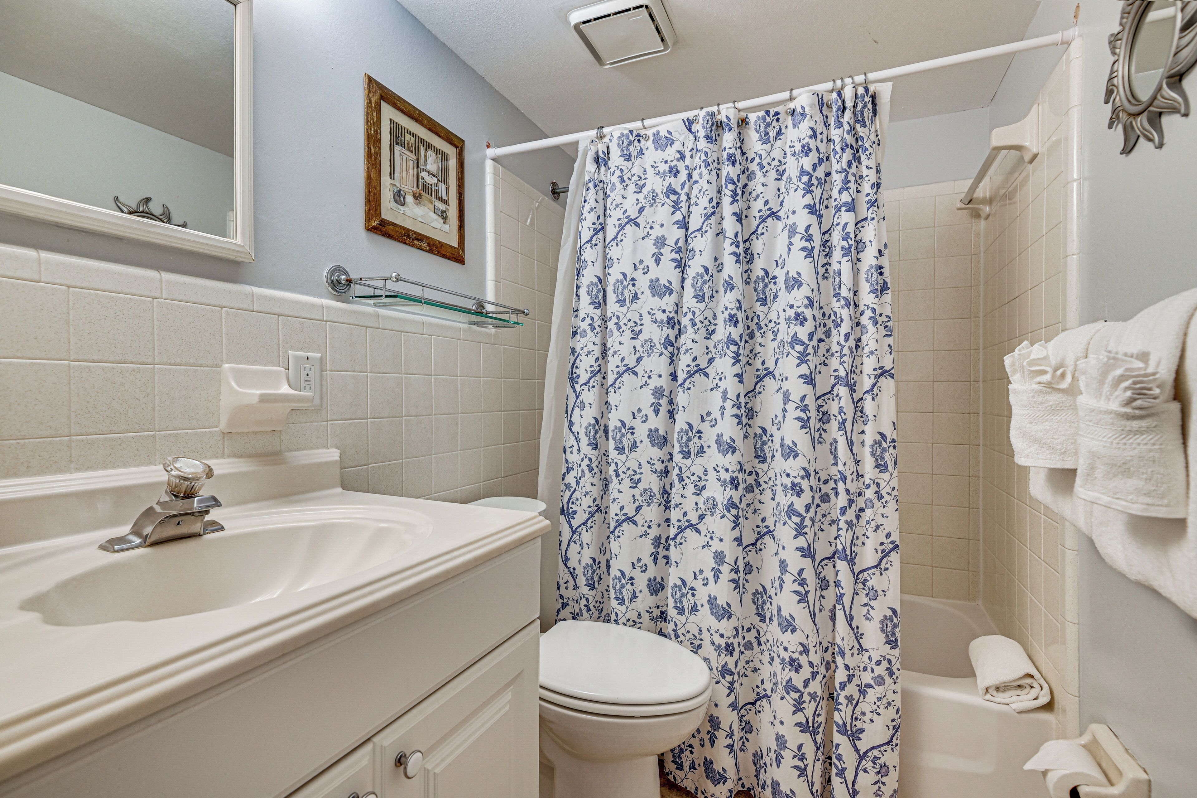 A bathroom with a bathtub, toilet, sink, and a shower curtain.