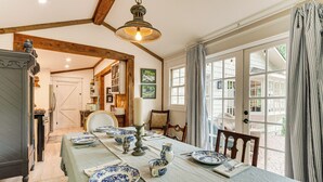 A dining room with a table set for four, a chandelier, and a view through a glass door.