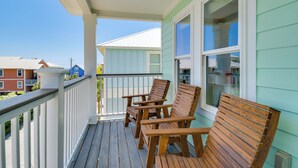Une terrasse en bois, avec des chaises, une rambarde et une vue sur les maisons voisines.
