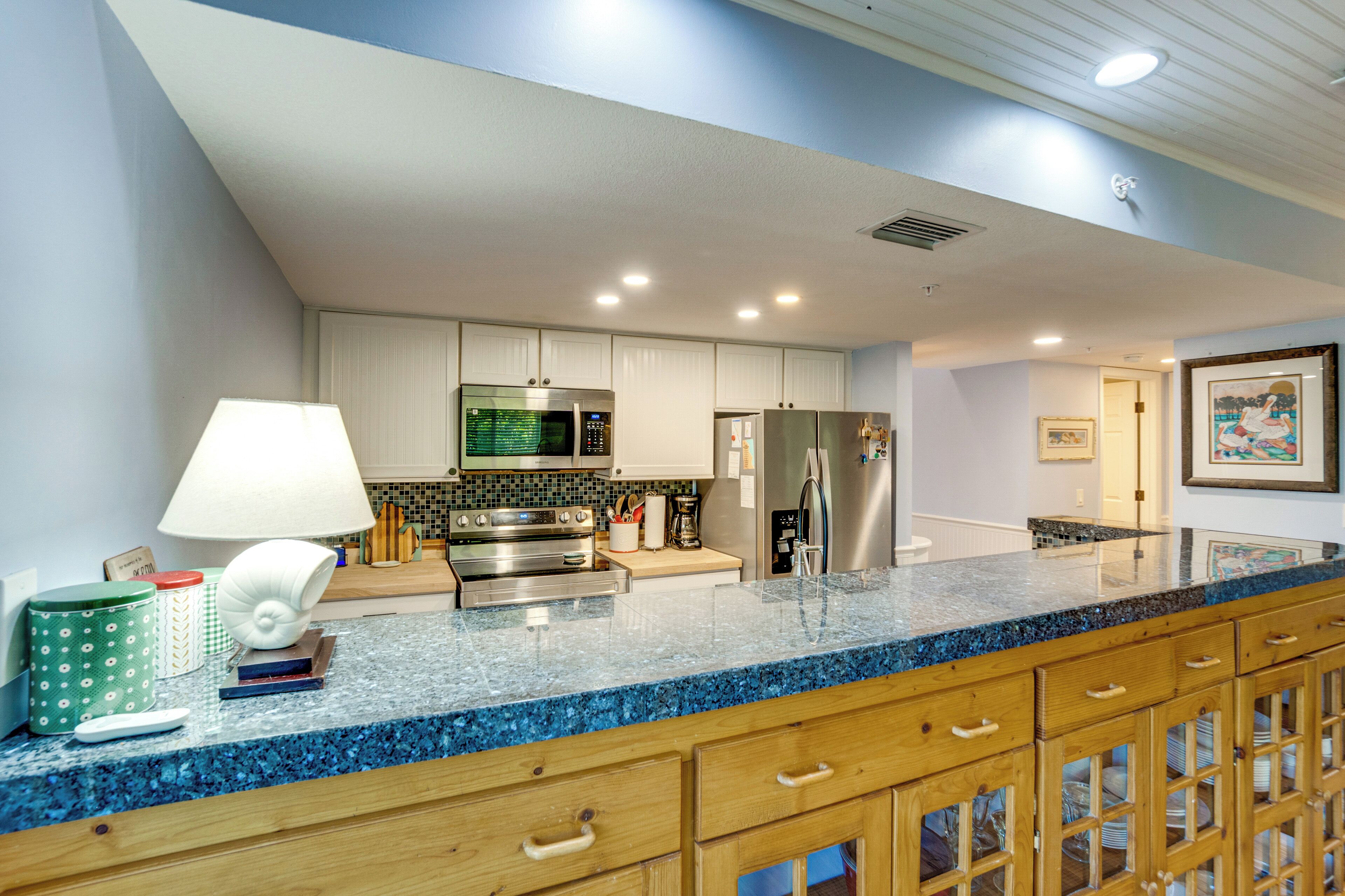 A kitchen with a blue granite countertop, stainless steel appliances, wooden cabinets, and a white ceiling.