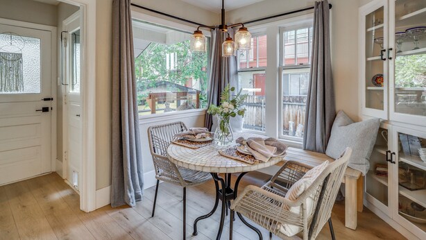 A dining area with wicker chairs, a round table, and a hanging light fixture. - Premium Modern Midtown Favorite: Walk to it All! (Reno)