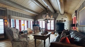 Ein gemütliches Wohnzimmer mit Kamin, Holzböden und einem großen Fenster.