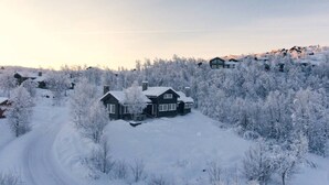 Schneebedeckte Landschaft mit Haus und umliegenden Bäumen.