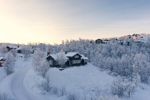 Schneebedeckte Landschaft mit Haus und umliegenden Bäumen.