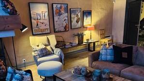 Ein gemütliches Wohnzimmer mit Sofa, Sesseln, Couchtisch und einem an der Wand befestigten Fernseher.