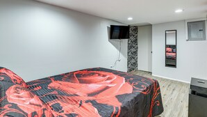 A bedroom with a bed, a TV mounted on the wall, a mirror, and a small cabinet. - Groups & Pets Welcome! Spacious Philly Rowhouse (Philadelphia)