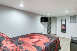 A bedroom with a bed, a TV mounted on the wall, a mirror, and a small cabinet. - Groups & Pets Welcome! Spacious Philly Rowhouse (Philadelphia)