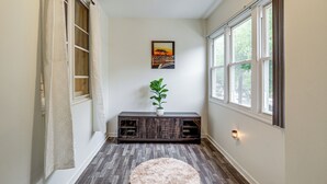 A hallway with a wooden floor, a round rug, a dark wooden bench with a plant, and a painting on the wall. - Groups & Pets Welcome! Spacious Philly Rowhouse (Philadelphia)