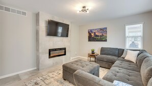Ein Wohnzimmer mit Ecksofa, Kamin, Wandfernseher und einem Bild an der Wand.