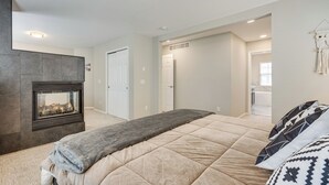 Ein Schlafzimmer mit Bett, Kamin, einer Tür und einem Flur, der zu einem Badezimmer führt.