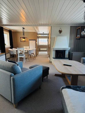 Et moderne interiør med sofa, spisebord og pejs.