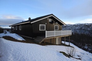 En træhytte med veranda og udsigt til sneklædte bjerge.