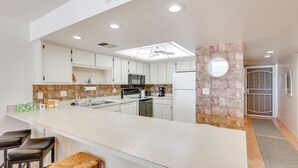 A modern kitchen with white cabinets, a large island with bar stools, a microwave, and a refrigerator. - Gulf-Front Gem w/ Pool Access on Fort Myers Beach! (Fort Myers Beach)