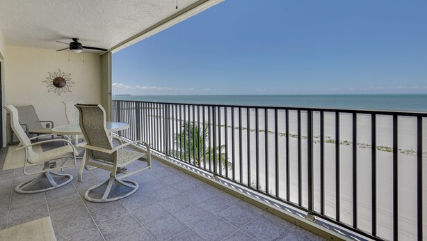 A balcony with a view of the sea, a ceiling fan, and two rocking chairs. - Gulf-Front Gem w/ Pool Access on Fort Myers Beach! (Fort Myers Beach)