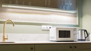 A kitchen with a gold faucet, a white microwave, and a coffee maker on the counter. - Deluxe Apartment with Balcony for 2 (Alicente)