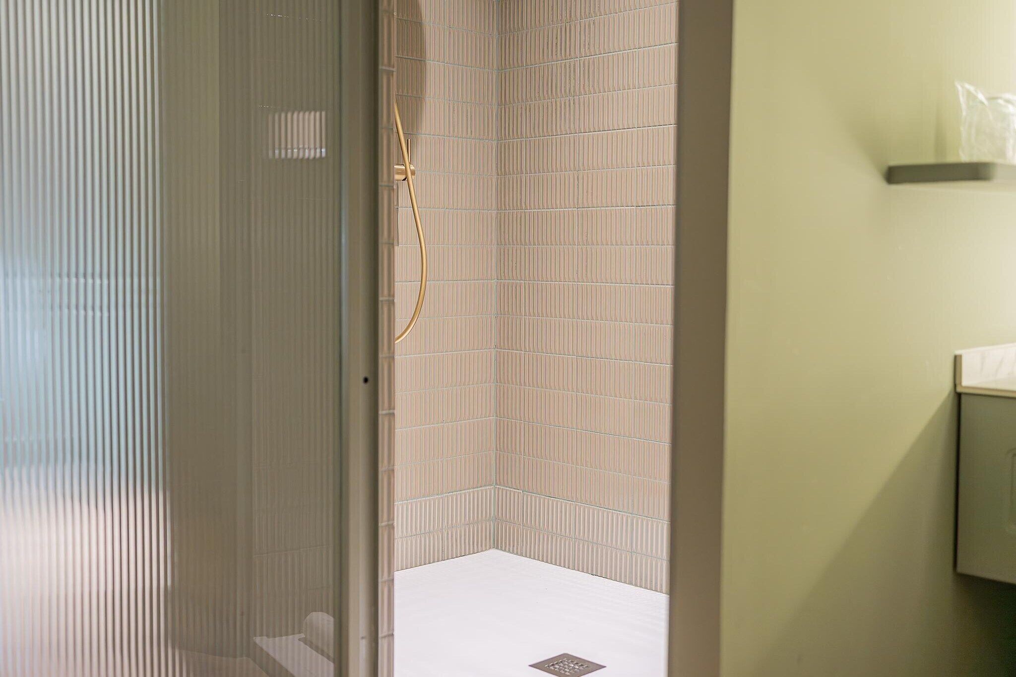 Ein Badezimmer mit Dusche, gefliesten Wänden und Toilette.