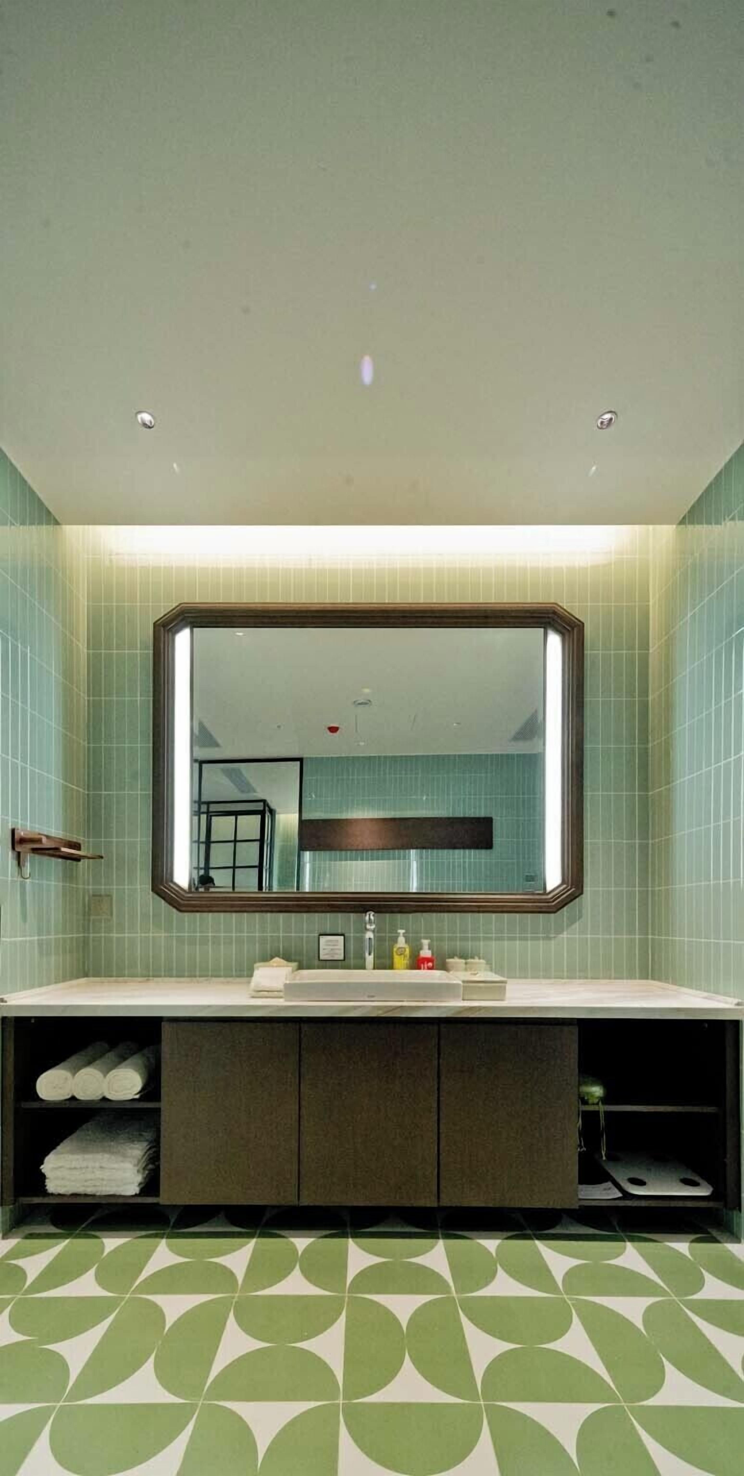 A bathroom with a large mirror, a sink, and a cabinet below.