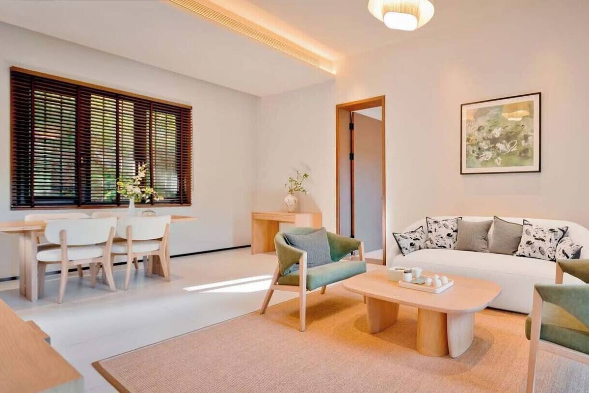 Una sala moderna con un sofá, sillas, una mesita de centro y un comedor con mesa y sillas.