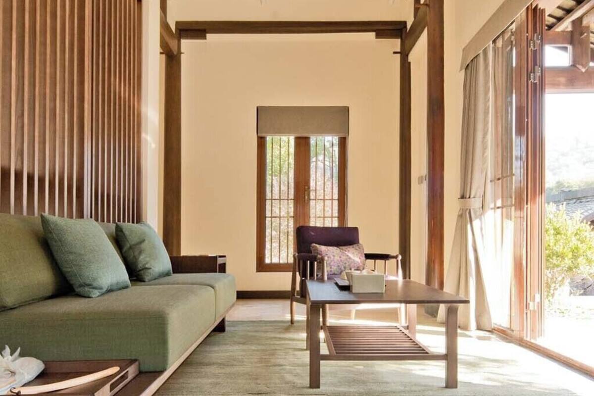 Una habitación con sofá, una mesa y una ventana con persianas.