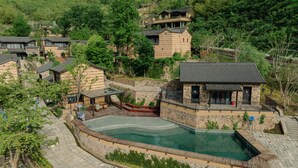 A residential area with a swimming pool, stone walls, and traditional-style houses. - ALOR VALLEY HUZHOU (Huzhou)