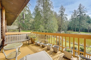 A wooden deck with a bench, a table, and potted plants.