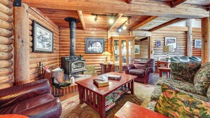 A log cabin interior with a fireplace, leather furniture, and framed pictures on the walls.