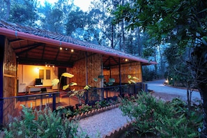 A wooden cabin with a balcony, surrounded by trees and plants.