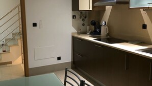 Cozinha moderna com mesa de jantar e cadeiras, cafeteira e micro-ondas.