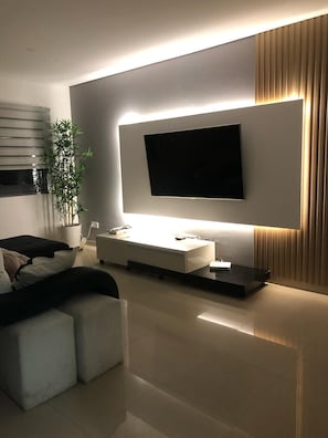Ein modernes Wohnzimmer mit einem an der Wand befestigten Flachbildfernseher, einem schlichten Konsolentisch und einem Sofa.