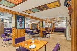 Een restaurant met houten lambrisering, paarse zitplaatsen en een menubord.