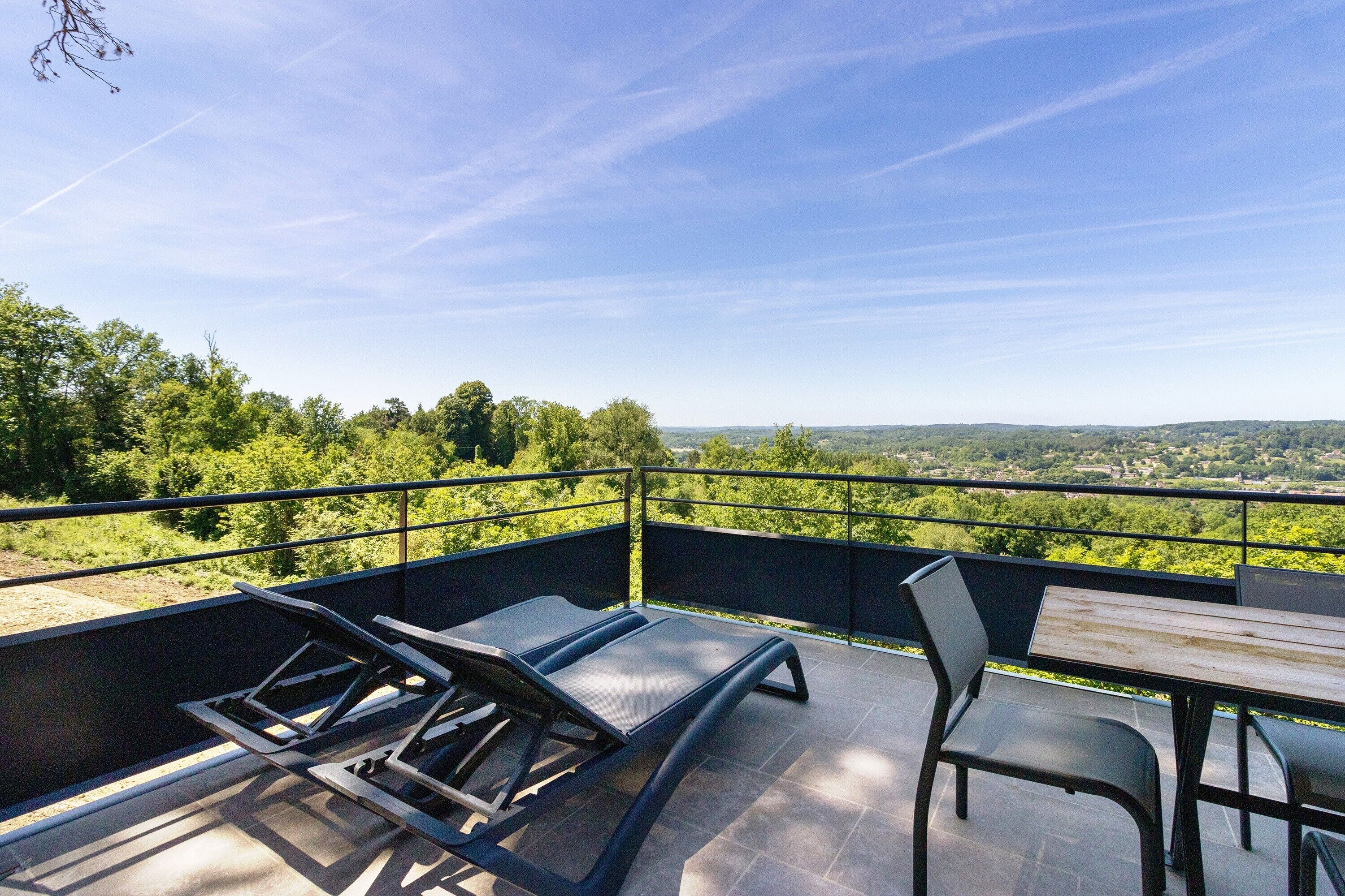 Una terraza con mesa y sillas, con vistas a un paisaje verde exuberante.